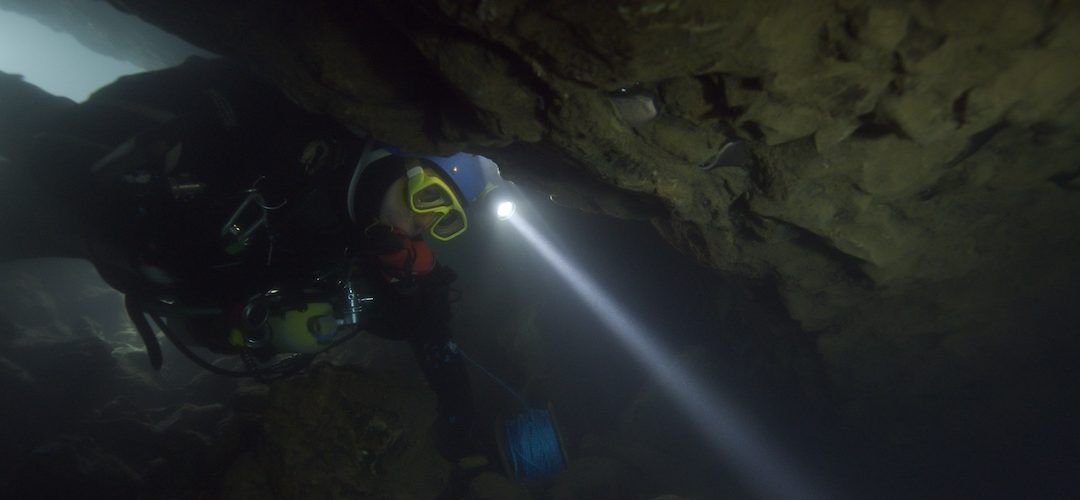 cave diver in darkness with light on head